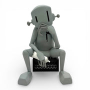 Gray robot sitting on a black box with a white object inside against a white background